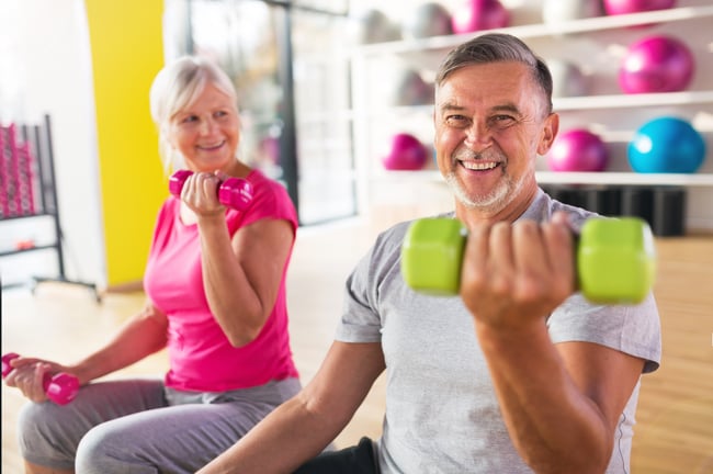 older couple smiling with hand weights