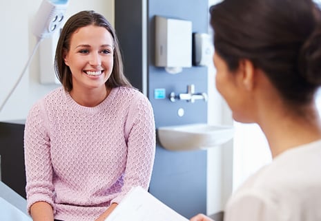 Happy young woman talks to doctor