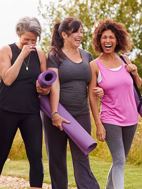 women laughing outside with yoga mats