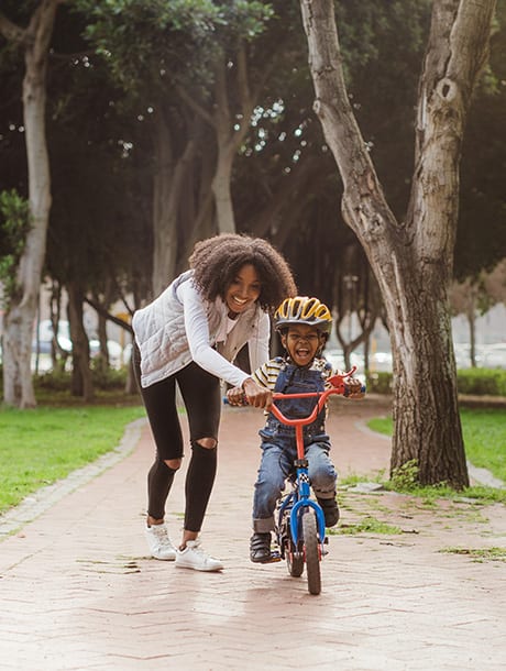 Mother teaching child how to ride a bike