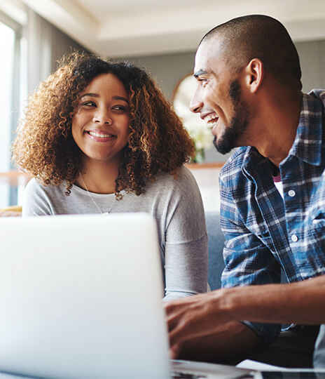 couple sitting on couch using laptop